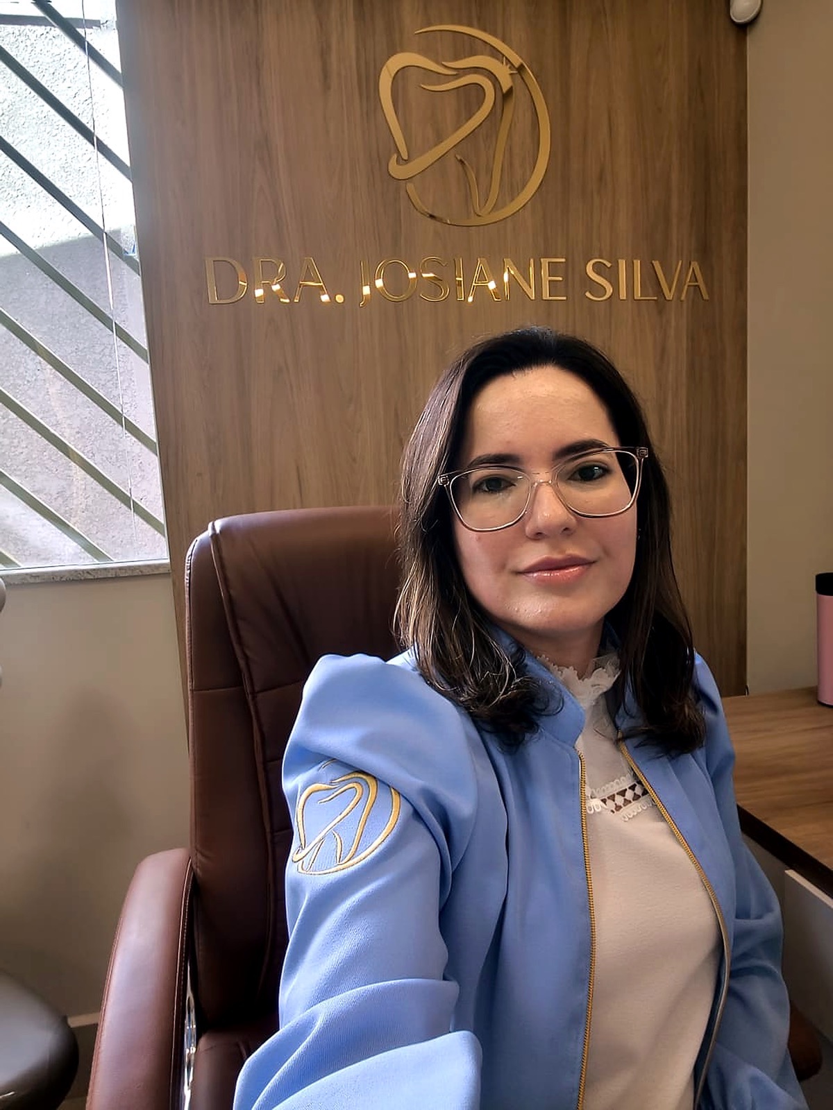 Dra. Josiane sentada em seu consultório odontológico